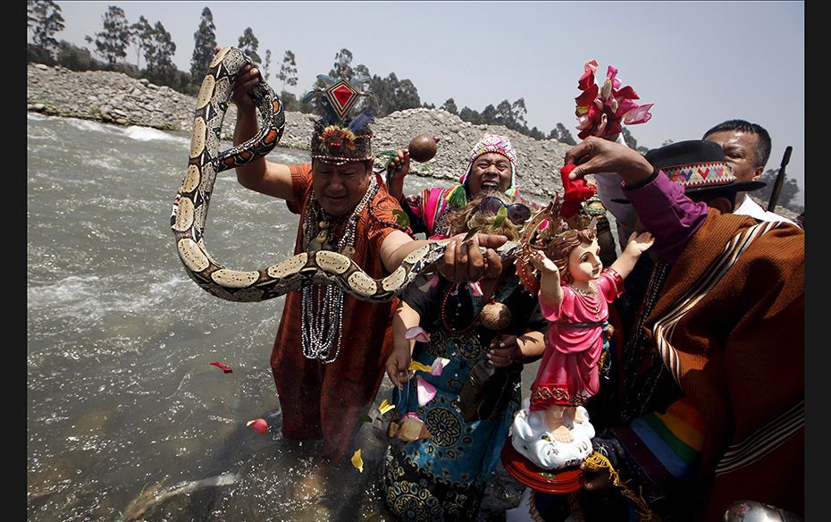 Peruvian shamans holding a figure of a Nino Jesus (Child Jesus) and a snake perform a ritual at the 