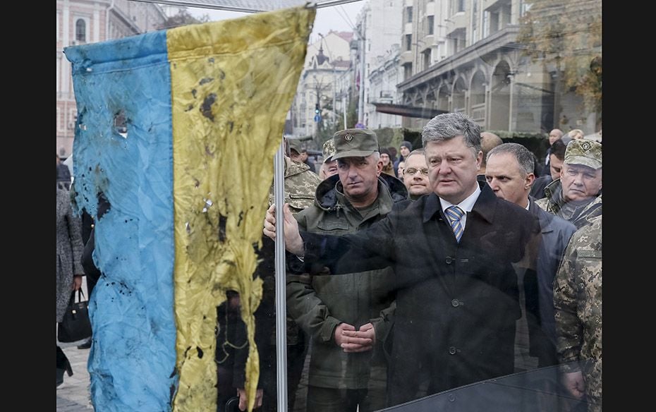 Ukraine's President Petro Poroshenko (C) looks at a Ukrainian flag brought from an eastern regio