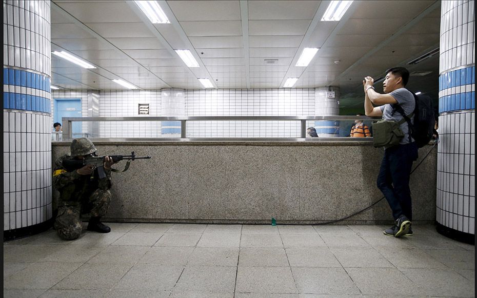 A South Korean soldier takes his position as a man photographs him during an anti-terror drill in Se