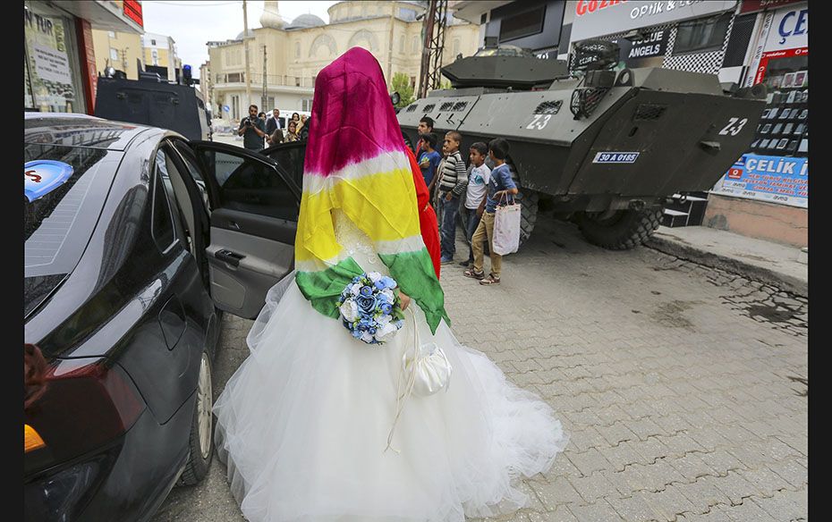 Bride Dilges Baskin, who has covered her face with a scarf in yellow-red-green Kurdish colours, gets