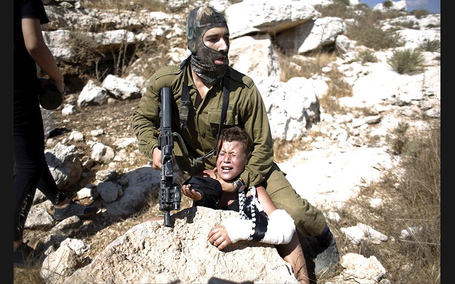 An Israeli soldier detains a Palestinian boy during a protest against Jewish settlements in the West