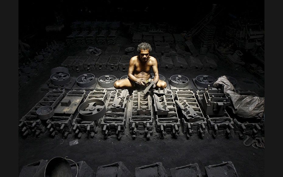 A labourer works inside the manufacturing unit of iron parts at a factory on the outskirts of Kolkat