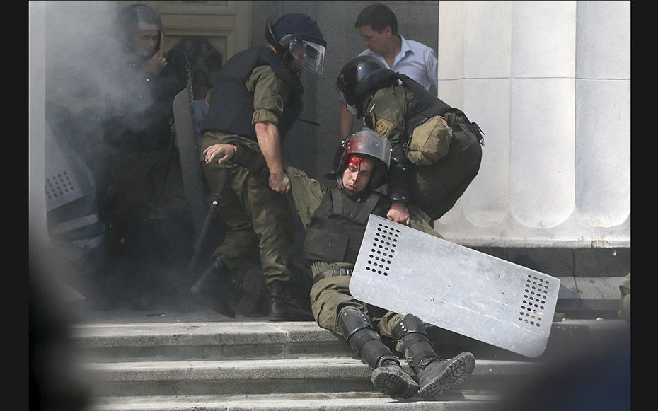 An injured national guard officer is carried away by comrades outside parliament in Kiev, Ukraine, o