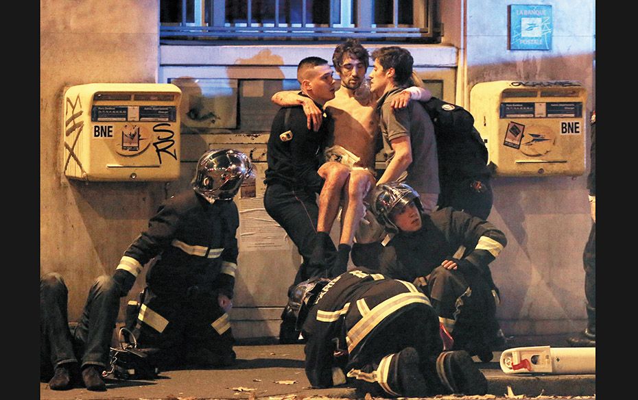 French fire brigade members help an injured man near the Bataclan concert hall following fatal shoot