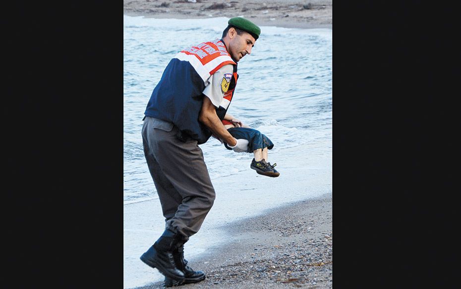 A police officer on a beach near Bodrum, Turkey,carries the dead body of Aylan Shenu, who drowned in