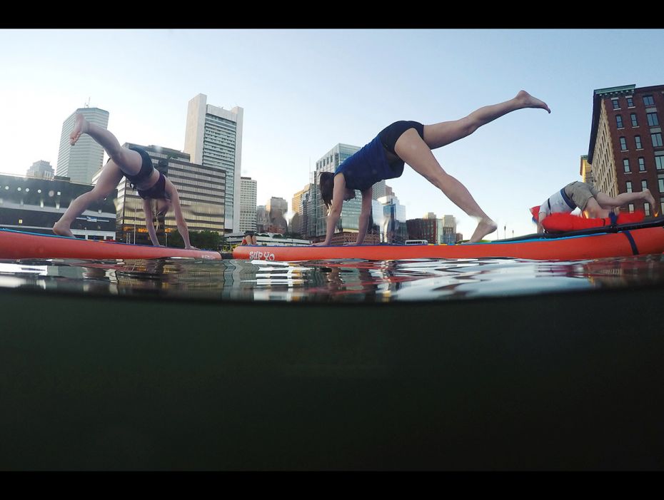 People take part in a "Sup Yo, Boston" stand up paddle board yoga class on Fort Point Chan