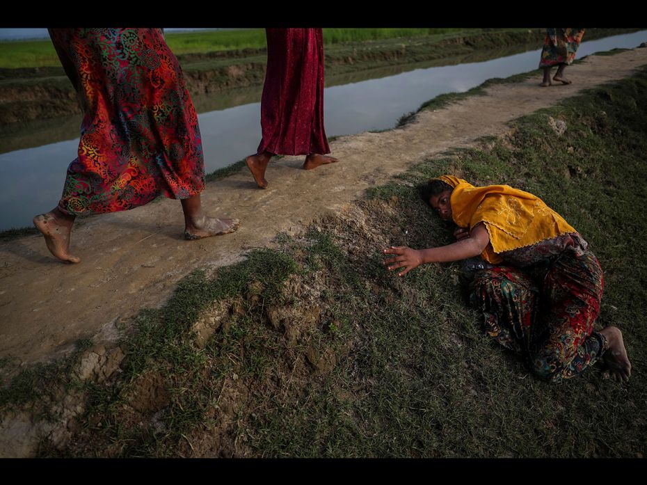 An exhausted Rohingya refugee fleeing violence in Myanmar cries for help from others crossing into P