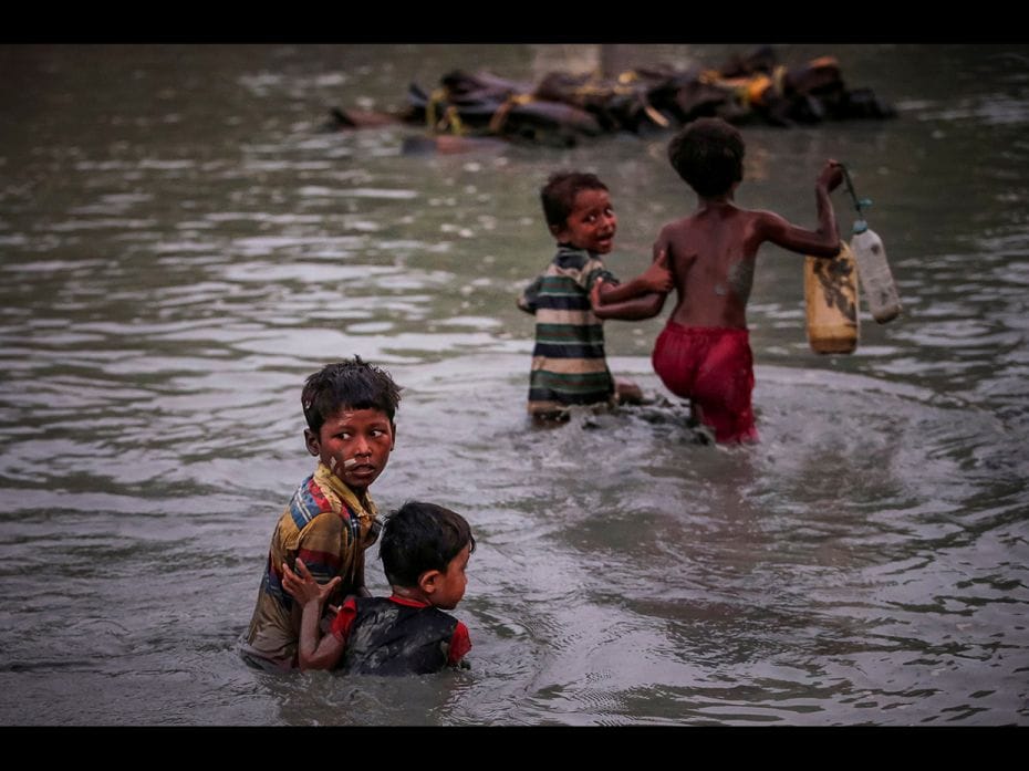 Rohingya siblings fleeing violence hold one another as they cross the Naf River along the Bangladesh