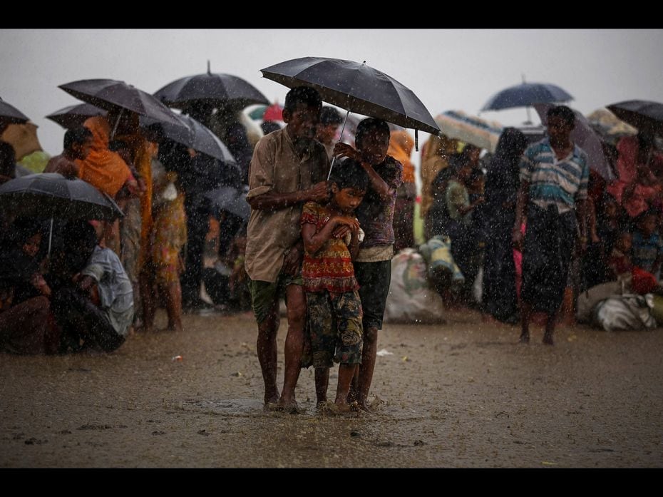 Rohingya refugees try to take shelter from torrential rain as they are held by the Border Guard Bang