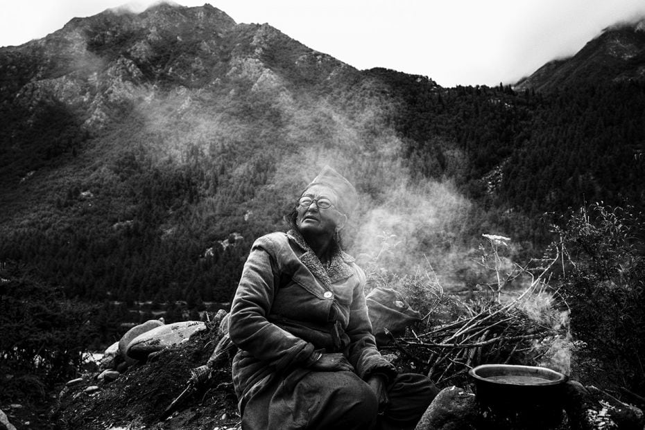 An old lady making tea for her family who is working at their fields in Chitkul Village, Himachal Pr