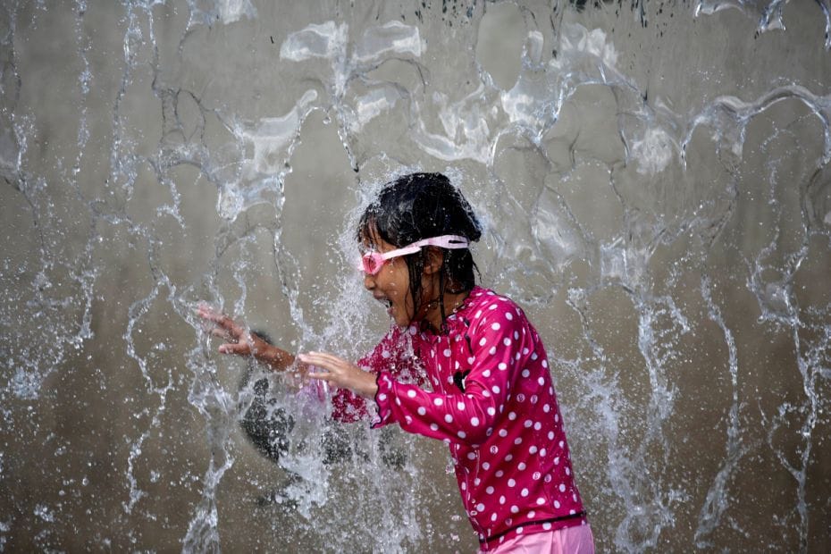 A young girl at a public fountain on a hot summer day in Tokyo. Roughly 125 have died in Japan as th