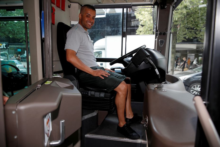 Bus driver Abdelkader poses in a bus wearing a bermuda, the new RATP uniform allowed during heat wav