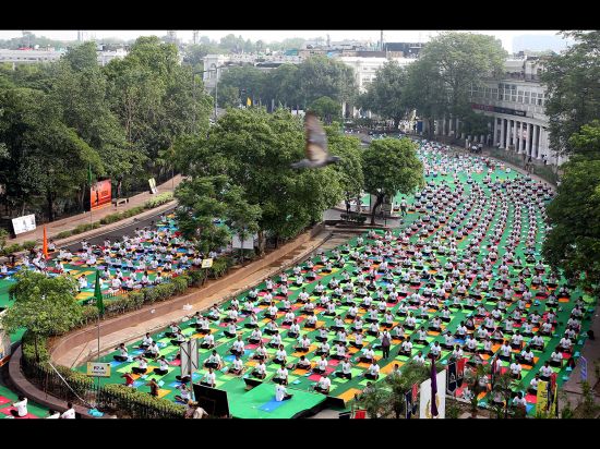 DELHI, INDIA - JUNE 21: Yoga practitioners gather at dawn in the inner circle of Connaught Place in 