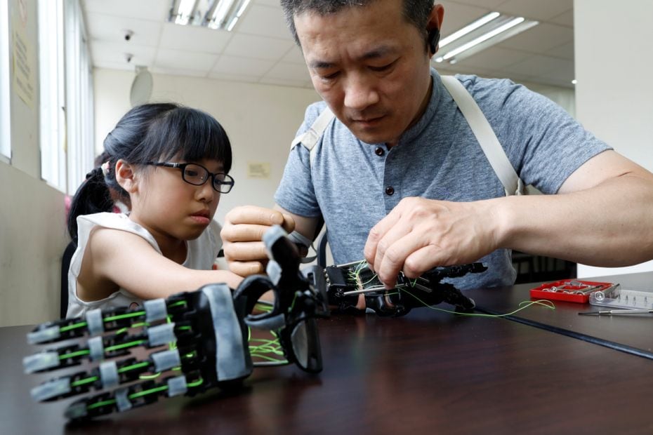 Engineer Chang Hsien-Liang, 46, fits a 3D-printed prosthetic hand, which he designed and built, on A