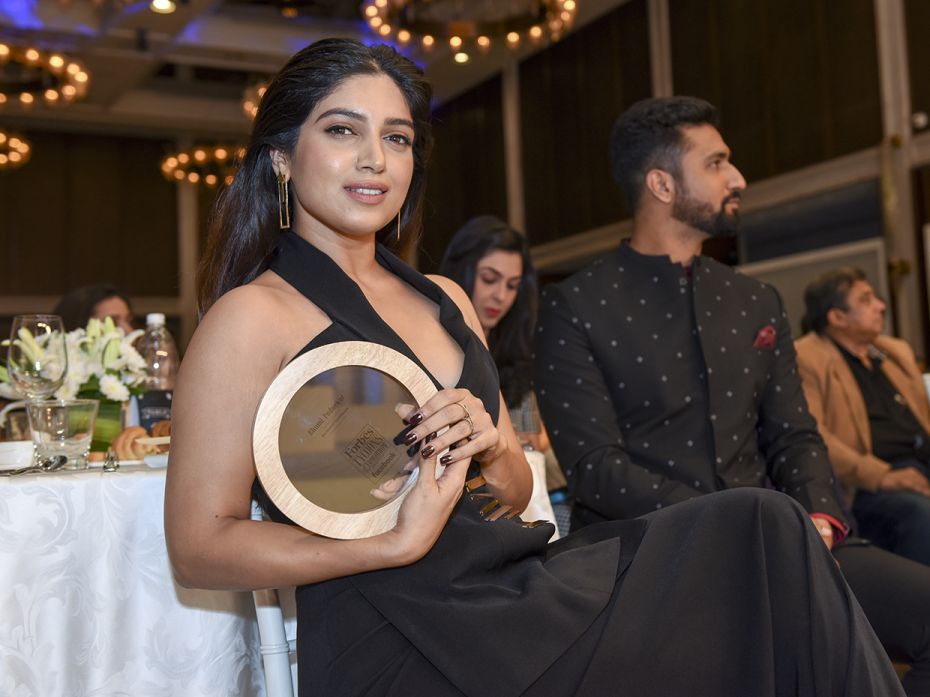 Actor Bhumi Pednekar poses with her plaque as Vicky Kaushal catches up on a panel discussion.https:/