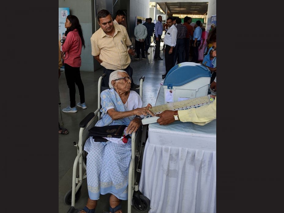 An Indian centenary voter (centre) tries a dummy voting machine in Ahmedabad at the 'Shatayu Sam