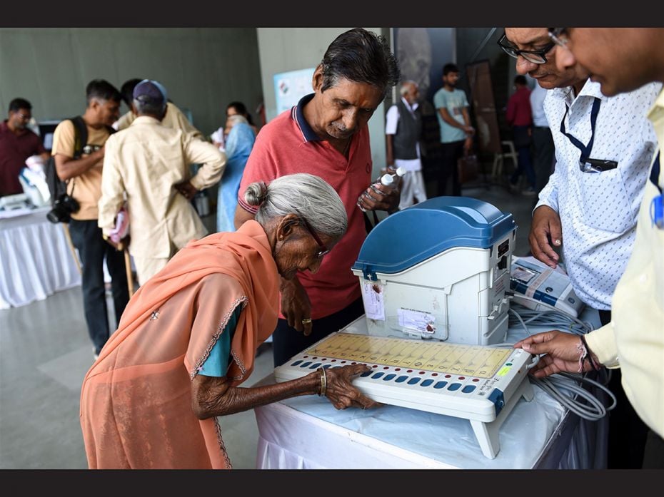 An Indian centenary voter (L) tries a dummy voting machine after she participated in 'Shatayu Sa