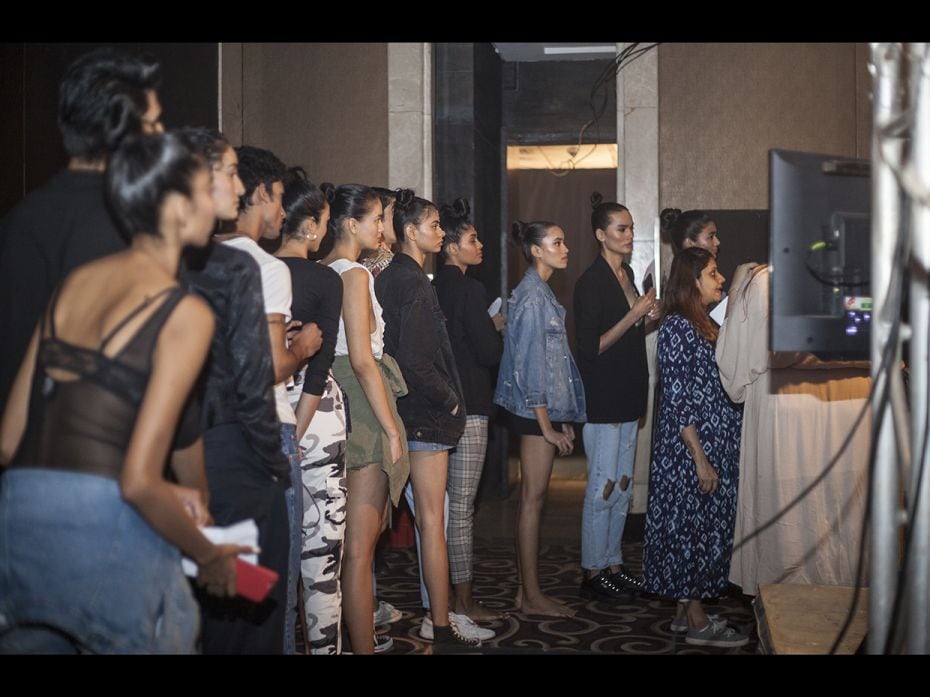 Models line up to get directions while rehearsing backstage before a show.