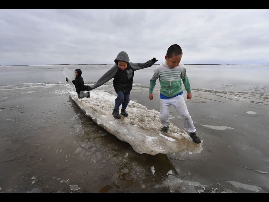 Schoolchildren play on melting ice at the climate change-affected Yupik Eskimo village of Napakiak o