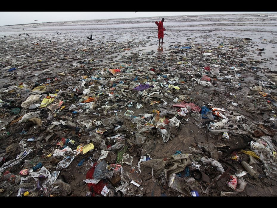 A man stands on a plastic waste at a beach in Mumbai, India on June 30, 2019. The trash was pushed o