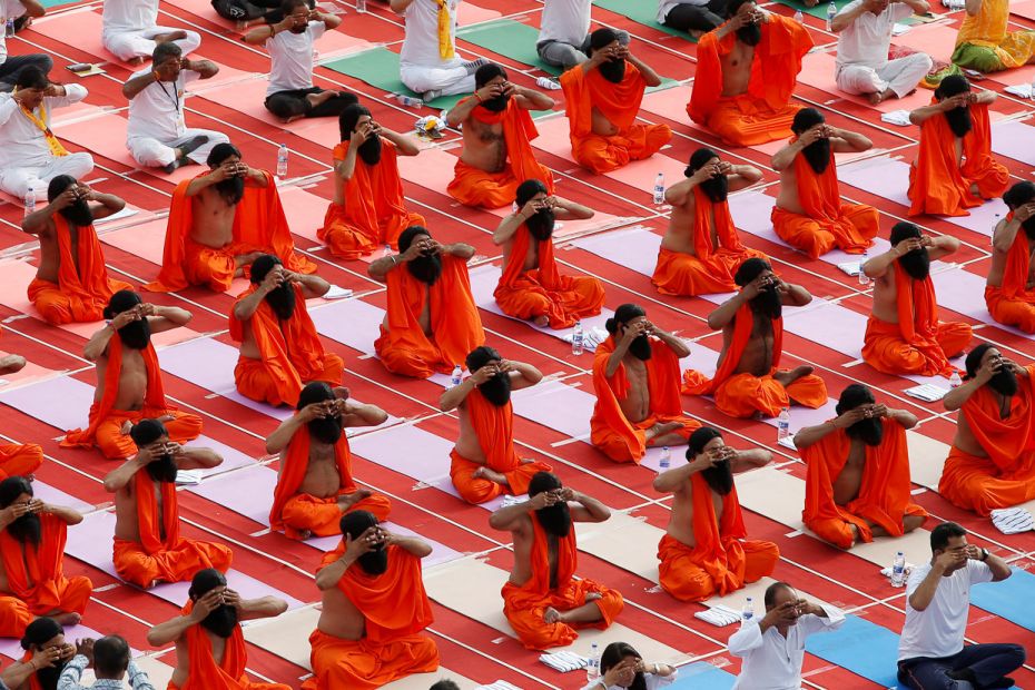 Participants dressed as sadhus perform yoga at a stadium during International Yoga Day in Ahmedabad