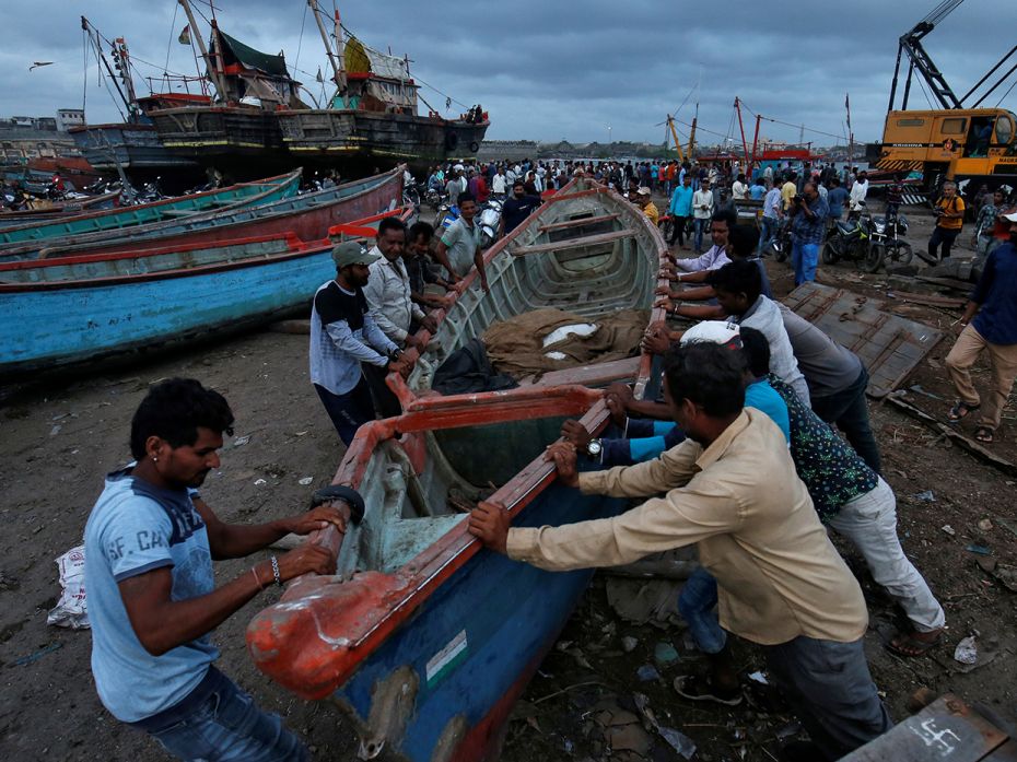 Fishermen team up to move a boat to a safer place along the shore, anticipating the worst.