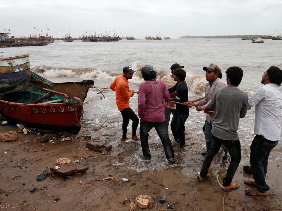 Fishermen try to lug a boat out of danger in the country’s fishing industries hub.