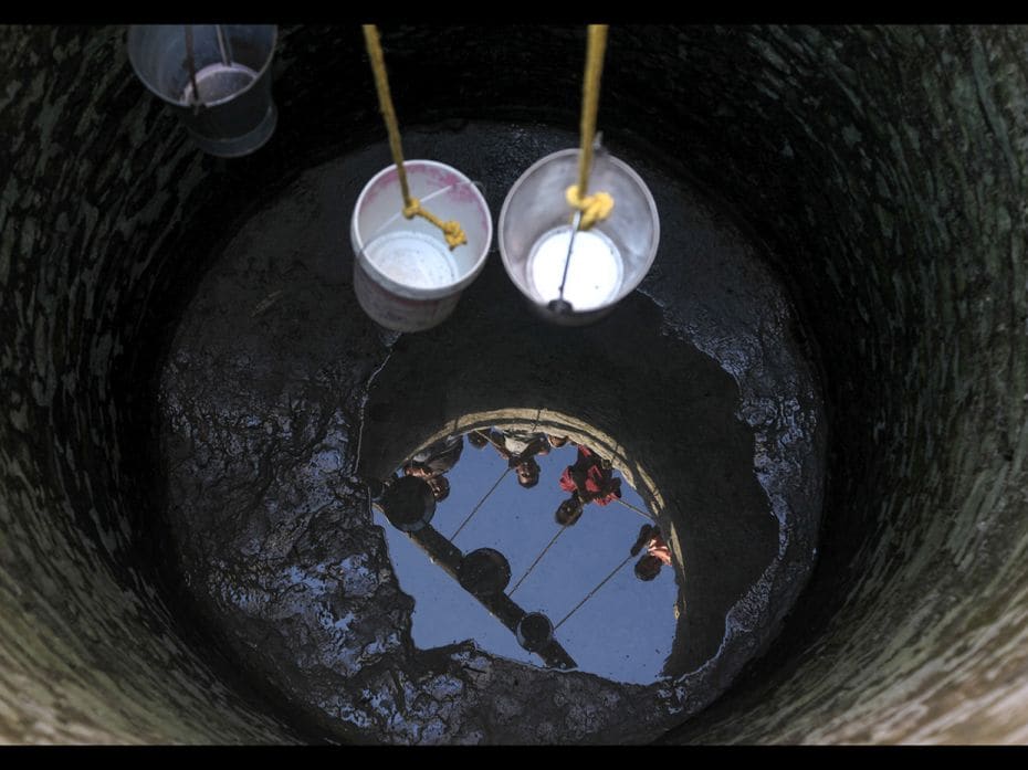 Jammu, India: Villagers take buckets down a well running dry, to collect drinking water at Padal vil