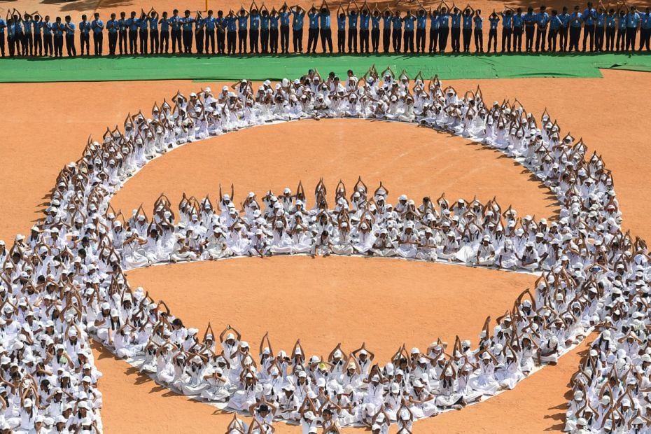 Indian school students sit in formation as they depict the cricket world cup, ahead of World Yoga Da