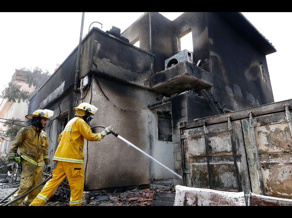 Mevo Modi'im, Israel: Firefighters spray water on embers around a damaged house, following a fir