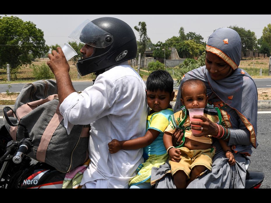 Haryana, India: An Indian family drink free, cold water on a highway during a hot afternoon at Garhi