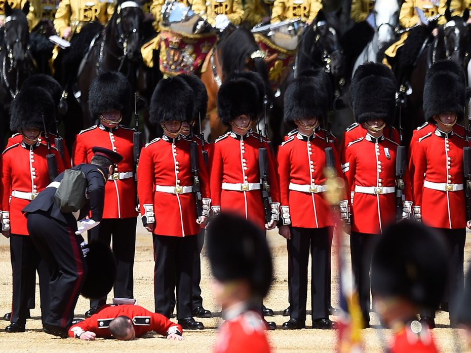 London, UK: A guardsman faints as the Household Division rehearse Trooping the Colour for the Colone