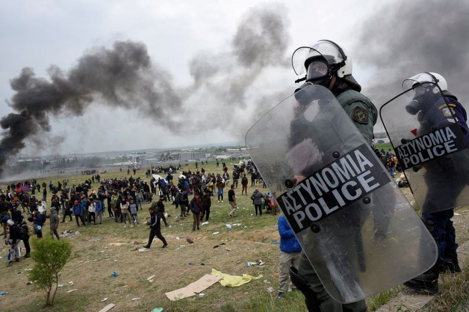 Riot police officers clash with refugees headed to Northern Europe outside a camp in the town of Dia