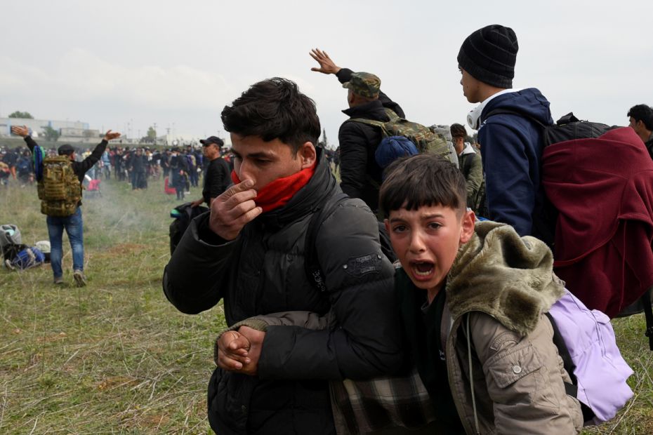 A young refugee is led away from a clash between migrants and authorities at a camp near the town of