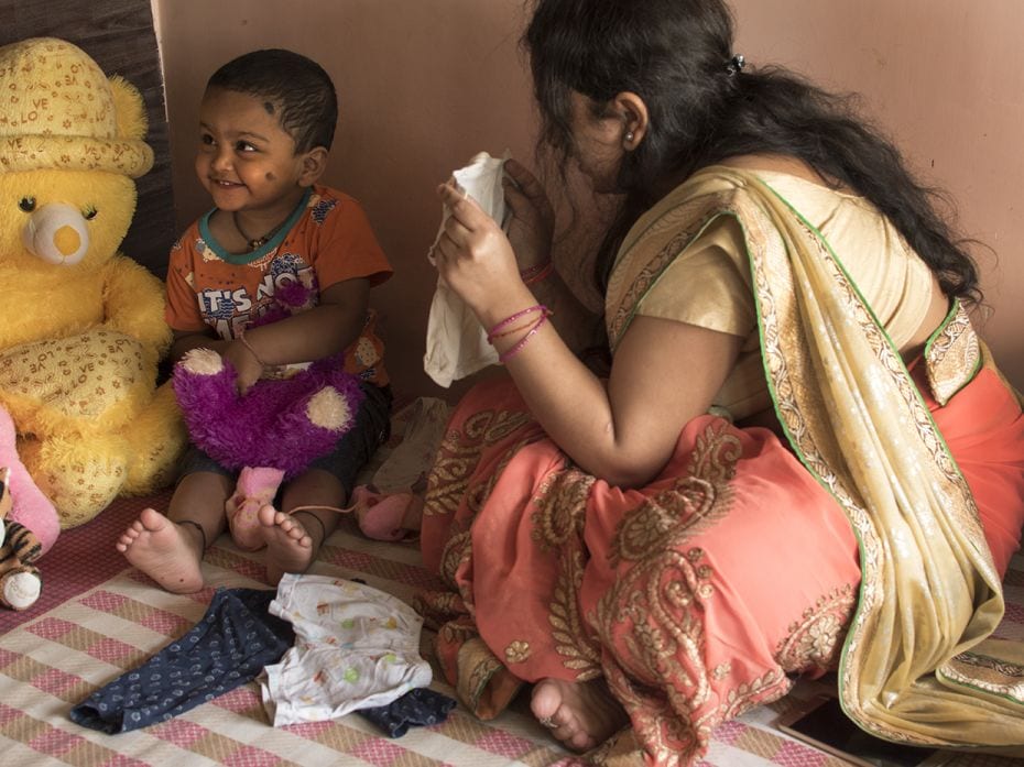 Shweta shows her daughter, Ananya (2), her first pair of clothes at their apartment in Mumbai. Shwet