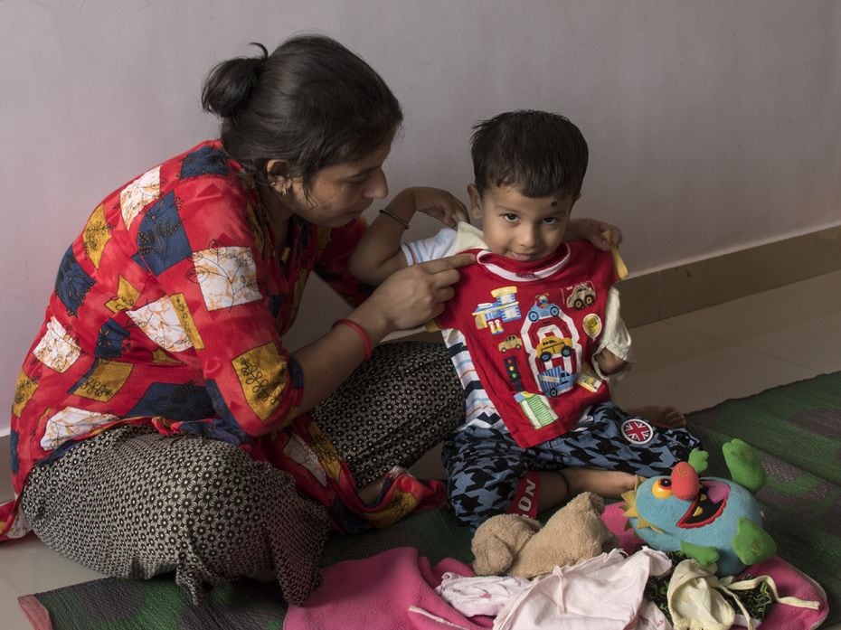 Rishab's (2) mother, Kavita, shows him his first-ever outfit at their home in Mumbai. Rishab is 