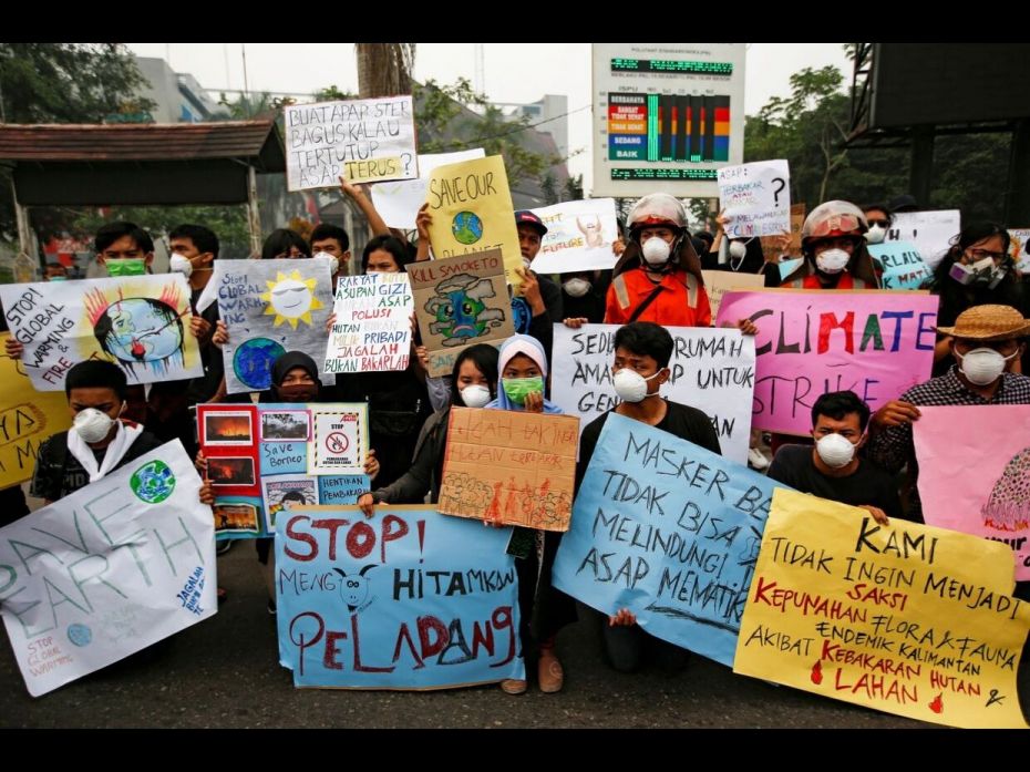 Youths with pollution masks gather with placards during a Global Climate Strike rally as smog covers