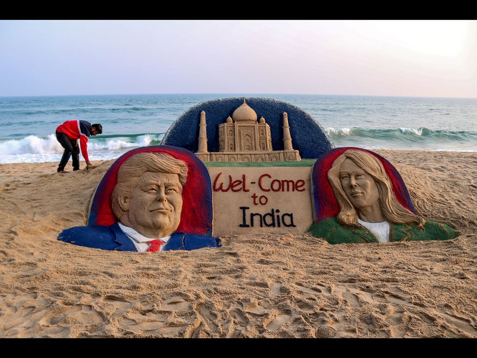 In this photo taken on February 22, 2020, artist Sudarsan Pattnaik (L) bends near his sand sculpture