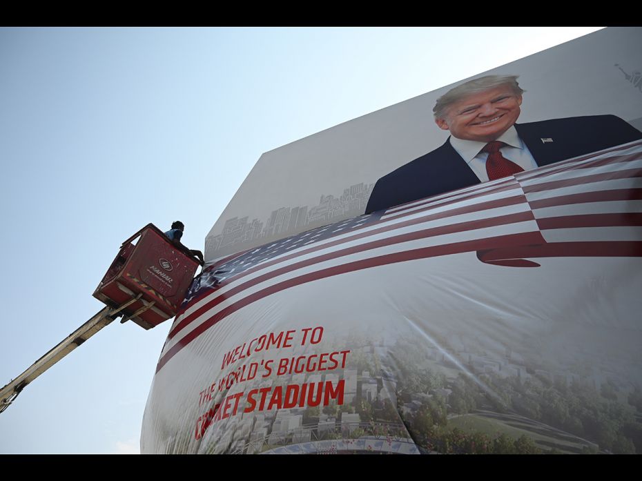 Workers placed a US national flag under a billboard displaying a picture of US President Donald Trum