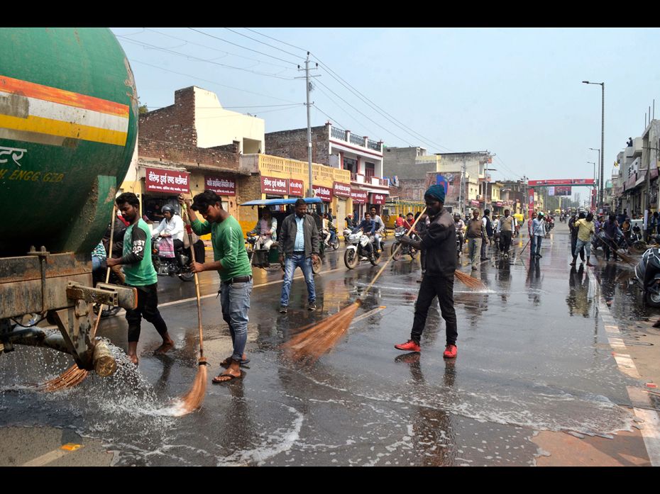 Workers wash a road with water near Kheria Airport in Agra on February 23, 2020, ahead of US Preside