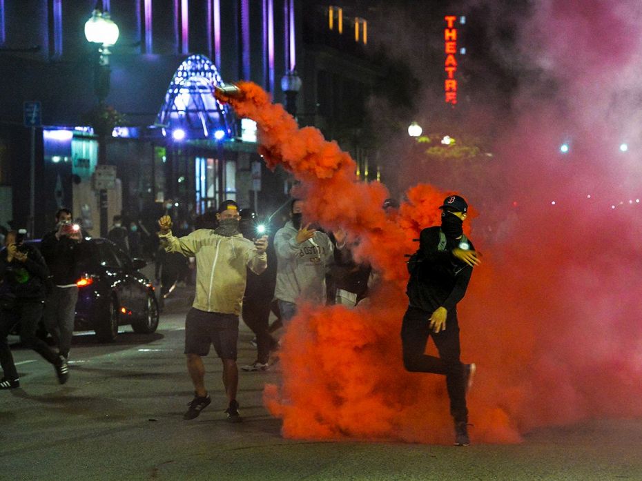 Protesters throw back smoke canisters during clashes with police during a demonstration over the dea