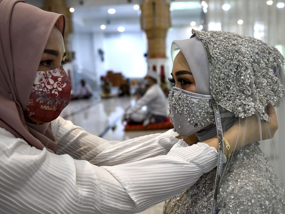 BANDA ACEH, INDONESIA – JUNE 3: A bride (R) is helped with her face mask amid the coronavirus 