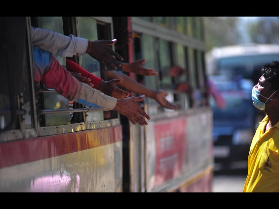 Migrant workers ask for eatables inside a bus to leave for their villages outside Allahabad bus stat