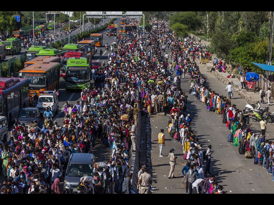 Crowds of Indian migrant workers wait to board buses to return to their native villages as a nationw