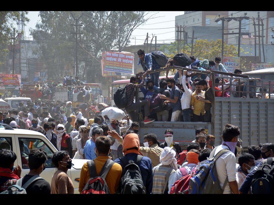 Migrant workers try to board a goods truck bound to their native state during Day 4 of the 21 day na