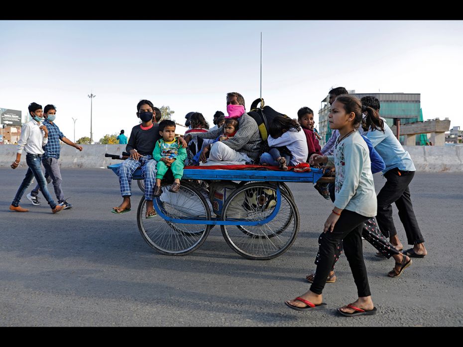 A migrant worker rides a cart with his family on a highway as they return to their villages, during 