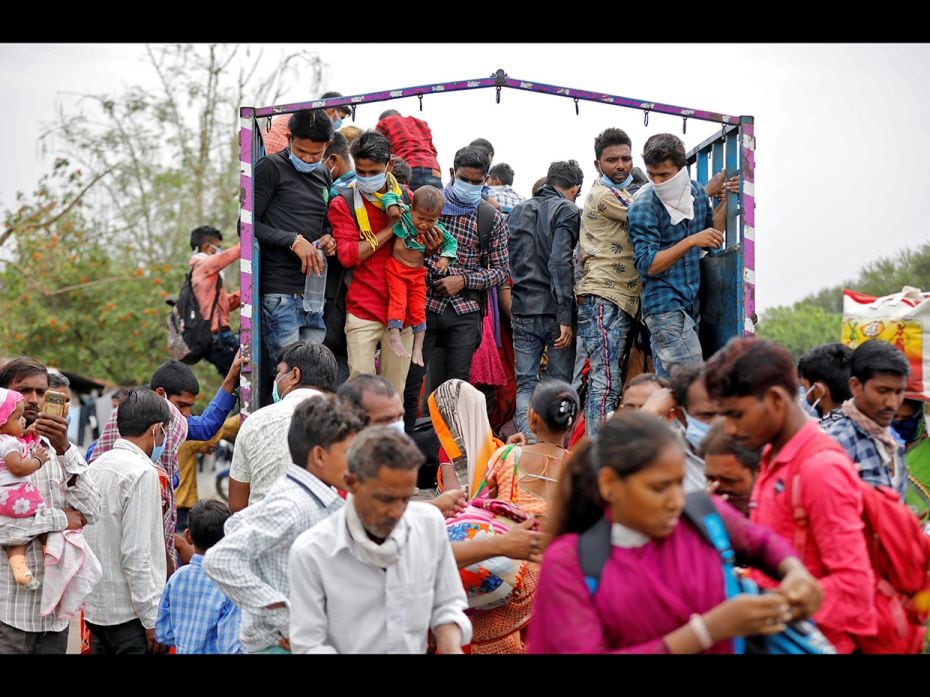 Migrant workers and their families board a truck in Ahmedabad to return to their villages after Indi