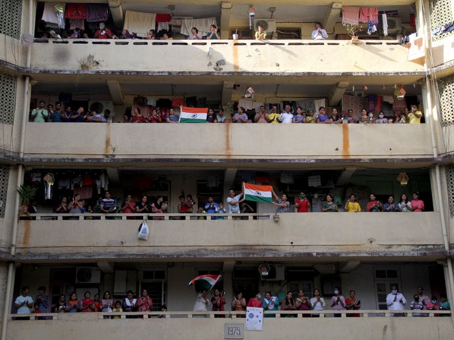 People cheer for essential service providers along with Indian flags, amidst the coronavirus pandemi