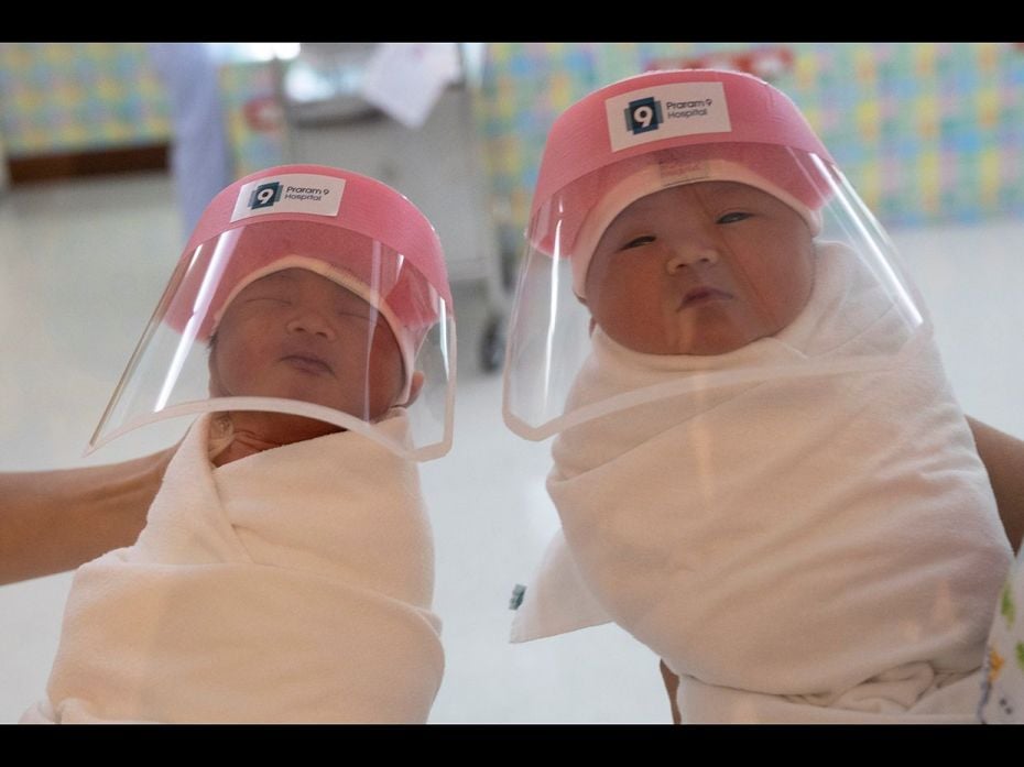 Nurses      hold newborn babies wearing protective face shields during  the coronavirus      disease