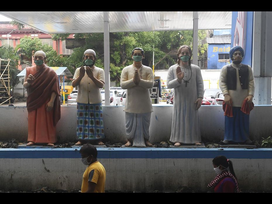 People walk past roadside statues representing different national religions on which local residents